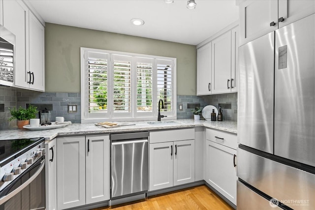 728 NW 189th Ln, Shoreline, WA 98177 - kitchen with appliances with stainless steel finishes, decorative backsplash, light stone counters, light wood-type flooring, and white cabinets