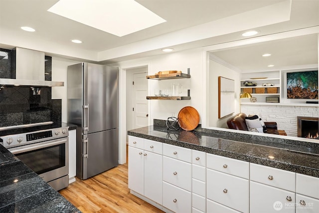 10261 NE 21st Pl, Bellevue, WA 98004 - kitchen featuring stainless steel appliances, tile counters, open shelves, wall chimney range hood, and white cabinets