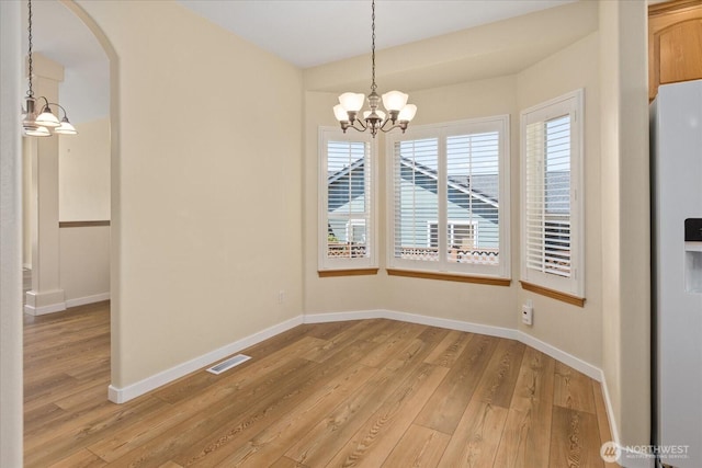 8051 283rd St NW, Stanwood, WA 98292 - unfurnished dining area with a chandelier, light wood-type flooring, and arched walkways
