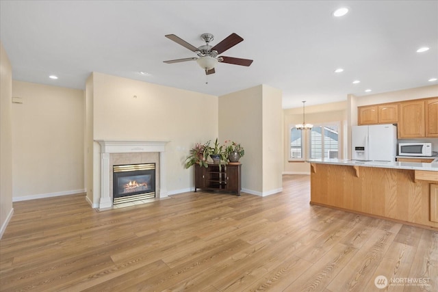 8051 283rd St NW, Stanwood, WA 98292 - kitchen featuring white appliances, a kitchen bar, open floor plan, a fireplace, and light wood-type flooring