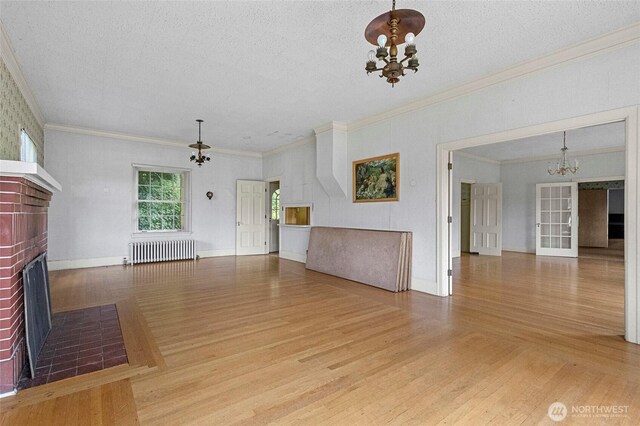 46372 E Main St, Concrete, WA 98237 - unfurnished living room featuring a chandelier, radiator, a brick fireplace, wood finished floors, and ornamental molding