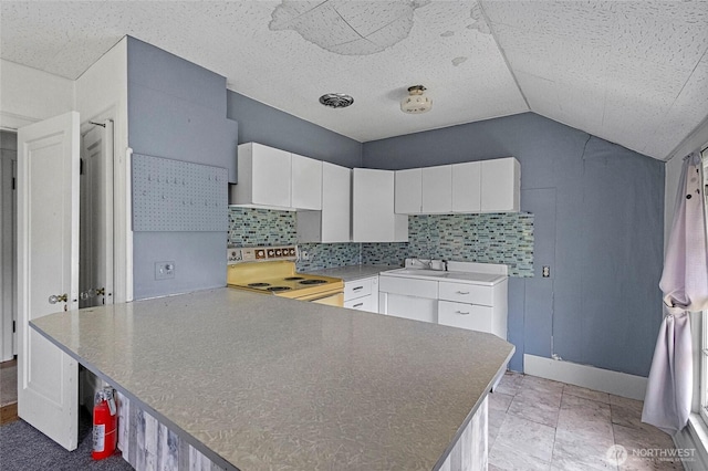 46372 E Main St, Concrete, WA 98237 - kitchen with electric range, a peninsula, white cabinets, vaulted ceiling, and tasteful backsplash
