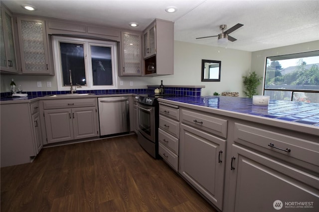 28635 11th Ave S, Federal Way, WA 98003 - kitchen featuring appliances with stainless steel finishes, dark wood-style floors, ceiling fan, glass insert cabinets, and gray cabinetry