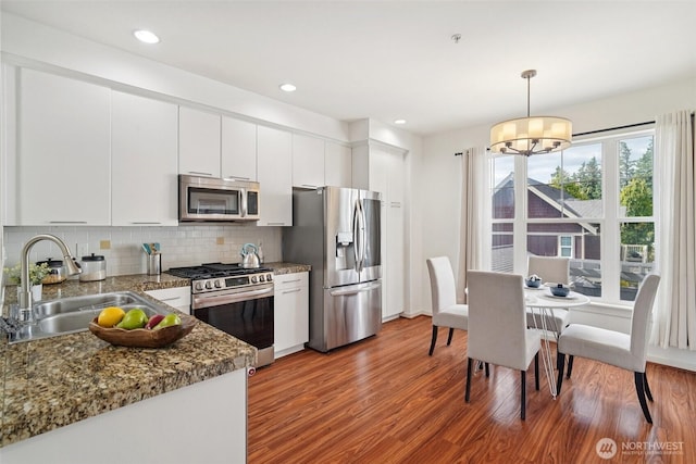 1899 NE Kenyon Ct, Issaquah, WA 98029 - kitchen featuring stainless steel appliances, wood finished floors, white cabinets, tasteful backsplash, and pendant lighting