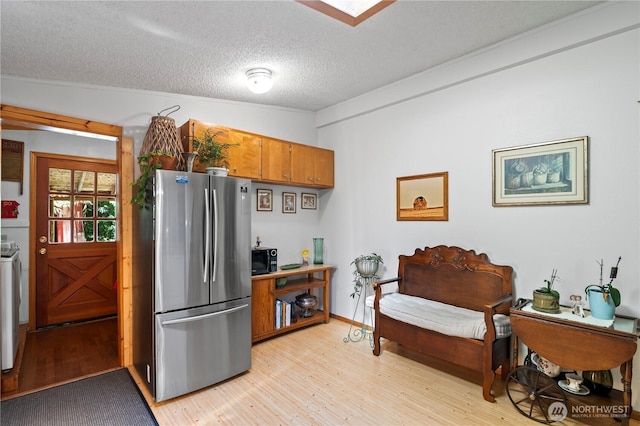 472 Iris Ln, Camano Island, WA 98282 - kitchen with freestanding refrigerator, light wood-type flooring, brown cabinets, a textured ceiling, and washer / dryer