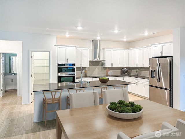 17911 139th Pl E, Puyallup, WA 98374 - kitchen with appliances with stainless steel finishes, wall chimney exhaust hood, dark countertops, tasteful backsplash, and an island with sink