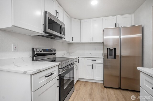 1308 133rd St S, Tacoma, WA 98444 - kitchen with appliances with stainless steel finishes, light stone counters, light wood finished floors, and white cabinets