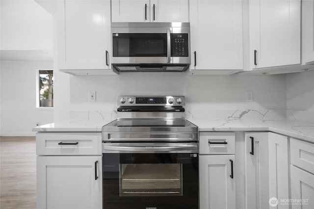 1308 133rd St S, Tacoma, WA 98444 - kitchen with stainless steel appliances, white cabinetry, light stone countertops, and light wood-style flooring