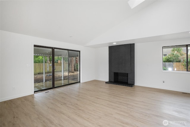 1308 133rd St S, Tacoma, WA 98444 - unfurnished living room with wood finished floors, high vaulted ceiling, a brick fireplace, and a skylight