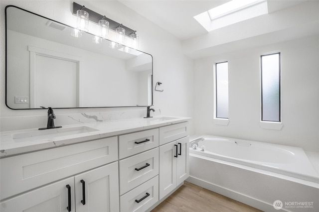 1308 133rd St S, Tacoma, WA 98444 - bathroom featuring a skylight, double vanity, a garden tub, and wood finished floors