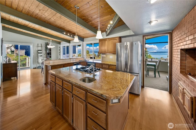 29812 Marine View Dr SW, Federal Way, WA 98023 - kitchen featuring freestanding refrigerator, a kitchen island with sink, light wood-style flooring, brown cabinets, and stovetop