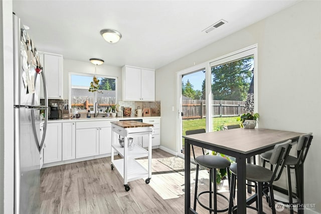 2427 Spruce Rd, Lake Stevens, WA 98258 - kitchen with freestanding refrigerator, tasteful backsplash, light wood-type flooring, and white cabinetry