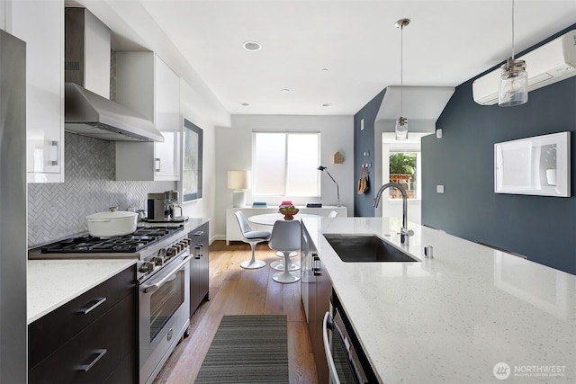 1117 34th Ave Unit B, Seattle, WA 98122 - kitchen featuring stainless steel stove, wall chimney range hood, dark wood-style floors, dark cabinetry, and decorative backsplash