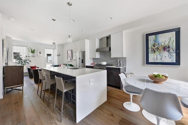 1117 34th Ave Unit B, Seattle, WA 98122 - kitchen featuring wall chimney range hood, white cabinets, light countertops, wood finished floors, and recessed lighting