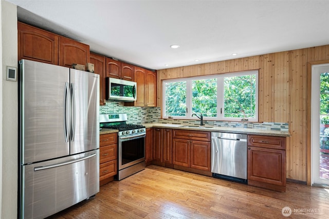 10122 50th Pl W, Mukilteo, WA 98275 - kitchen featuring appliances with stainless steel finishes, tasteful backsplash, brown cabinetry, light wood-style flooring, and light stone counters