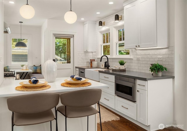 6518 18th Ave NE, Seattle, WA 98115 - kitchen featuring stainless steel microwave, a kitchen bar, white cabinetry, backsplash, and plenty of natural light