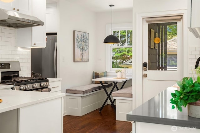6518 18th Ave NE, Seattle, WA 98115 - kitchen with under cabinet range hood, stainless steel range with gas cooktop, dark wood-style floors, tasteful backsplash, and white cabinets