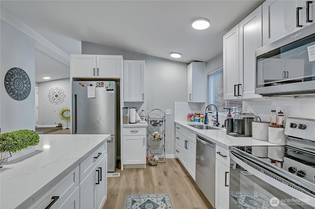 10707 209th Ave E, Bonney Lake, WA 98391 - kitchen featuring stainless steel appliances, white cabinets, light wood-style floors, light stone countertops, and vaulted ceiling