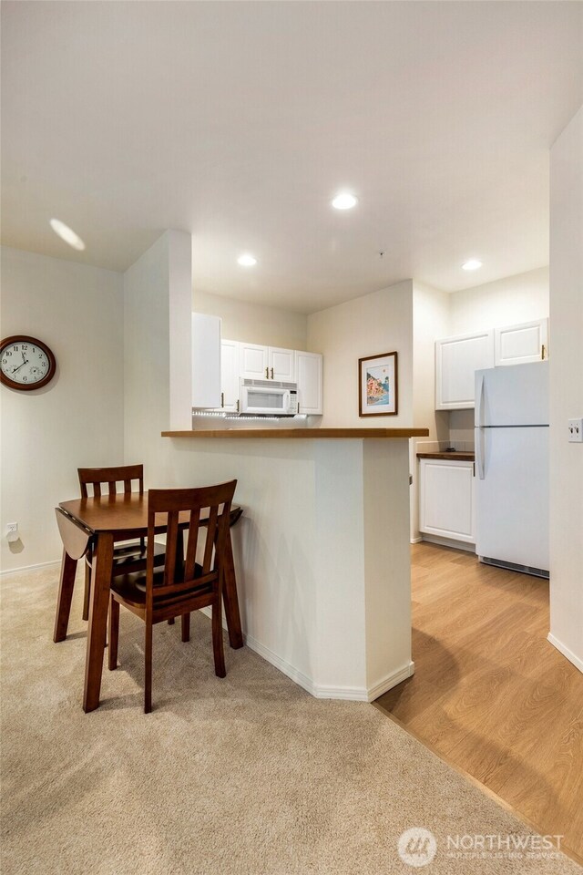 12712 Admiralty Way Unit B202, Everett, WA 98204 - kitchen featuring white appliances, white cabinetry, recessed lighting, a peninsula, and a breakfast bar area