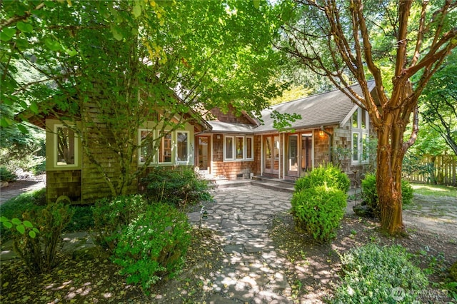 5579 NE Foster Rd, Bainbridge Island, WA 98110 - back of house with a porch, a shingled roof, and stone siding