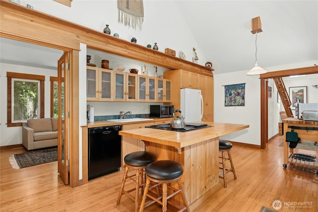 5579 NE Foster Rd, Bainbridge Island, WA 98110 - kitchen featuring black appliances, wood counters, a breakfast bar, high vaulted ceiling, and glass insert cabinets