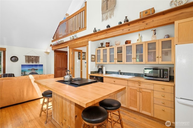 5579 NE Foster Rd, Bainbridge Island, WA 98110 - kitchen featuring wooden counters, black appliances, a kitchen breakfast bar, light wood finished floors, and high vaulted ceiling