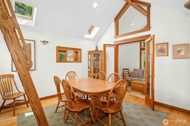 5579 NE Foster Rd, Bainbridge Island, WA 98110 - dining room featuring a skylight, french doors, light wood-style flooring, and high vaulted ceiling