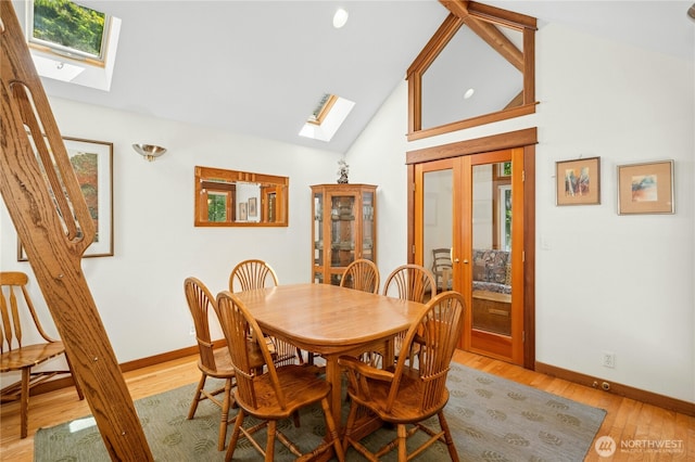 5579 NE Foster Rd, Bainbridge Island, WA 98110 - dining area with a skylight, french doors, light wood finished floors, and high vaulted ceiling