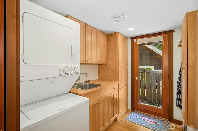 5579 NE Foster Rd, Bainbridge Island, WA 98110 - washroom featuring stacked washer / drying machine, cabinet space, and light wood-style flooring