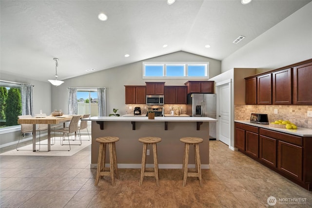 1330 Caprio Loop, Walla Walla, WA 99362 - kitchen featuring appliances with stainless steel finishes, light countertops, a breakfast bar, decorative backsplash, and decorative light fixtures