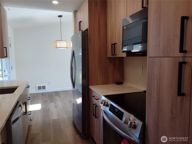 6245 S Huson St, Tacoma, WA 98409 - kitchen featuring stainless steel appliances, wood finished floors, light stone counters, modern cabinets, and recessed lighting
