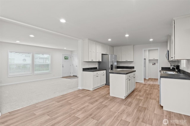 2120 77th Street Ct E, Tacoma, WA 98404 - kitchen with stainless steel appliances, a kitchen island, dark countertops, white cabinets, and light wood finished floors