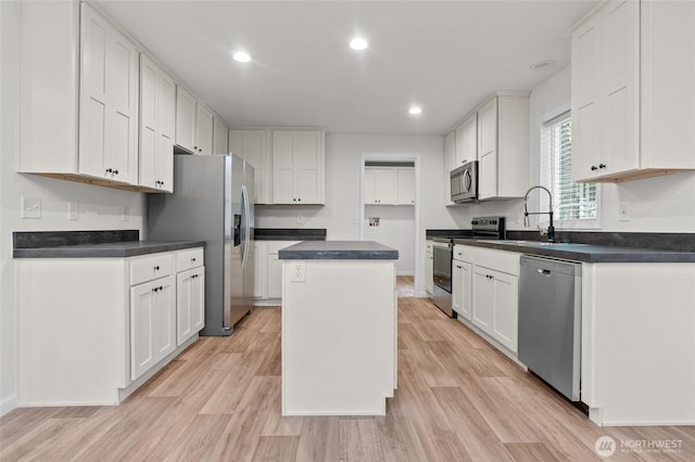 2120 77th Street Ct E, Tacoma, WA 98404 - kitchen featuring appliances with stainless steel finishes, a center island, light wood finished floors, white cabinets, and dark countertops