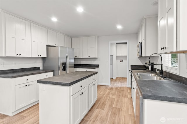 2120 77th Street Ct E, Tacoma, WA 98404 - kitchen featuring appliances with stainless steel finishes, light wood finished floors, dark countertops, white cabinetry, and a center island