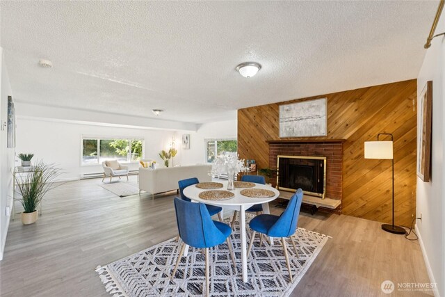 19520 Grannis Rd, Bothell, WA 98012 - dining space featuring wooden walls, wood finished floors, a textured ceiling, a brick fireplace, and a baseboard radiator
