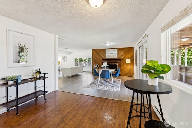 19520 Grannis Rd, Bothell, WA 98012 - living room with wood finished floors, a textured ceiling, wood walls, baseboard heating, and a fireplace