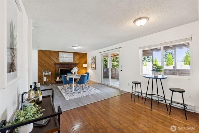 19520 Grannis Rd, Bothell, WA 98012 - dining space with a textured ceiling, wooden walls, wood finished floors, and a brick fireplace