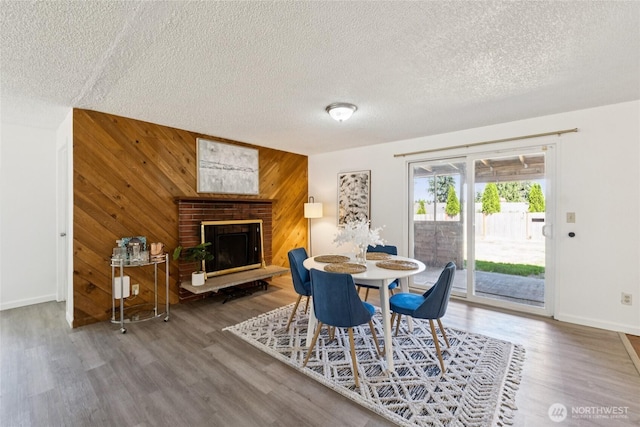 19520 Grannis Rd, Bothell, WA 98012 - dining space featuring wood finished floors, a textured ceiling, wooden walls, and a fireplace