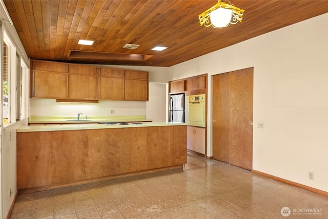 4728 86th Ave SE, Mercer Island, WA 98040 - kitchen featuring freestanding refrigerator, brown cabinetry, white oven, a peninsula, and light countertops