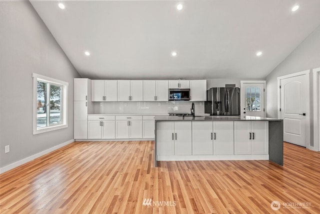 970 9th Ave, Longview, WA 98632 - kitchen featuring stainless steel appliances, lofted ceiling, white cabinetry, a kitchen island with sink, and light wood-type flooring