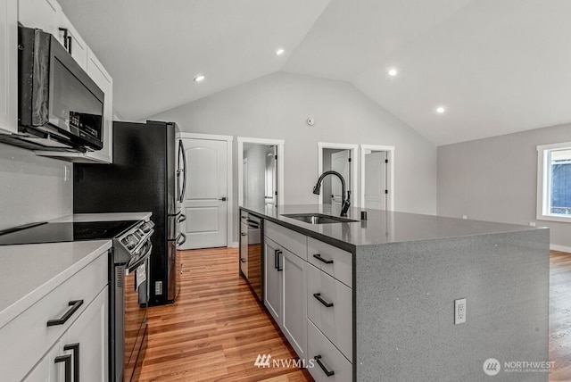 970 9th Ave, Longview, WA 98632 - kitchen featuring stainless steel appliances, light wood-style flooring, vaulted ceiling, a center island with sink, and white cabinetry