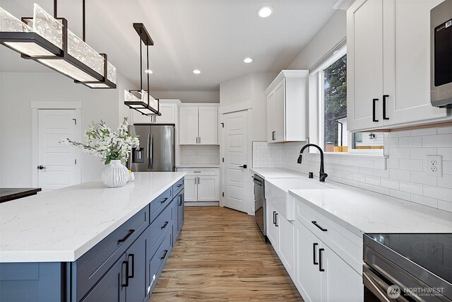 10111 12th Ave E, Tacoma, WA 98445 - kitchen featuring appliances with stainless steel finishes, recessed lighting, white cabinetry, light wood-type flooring, and a kitchen island