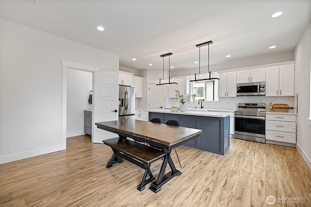 10111 12th Ave E, Tacoma, WA 98445 - kitchen featuring stainless steel appliances, white cabinetry, light wood finished floors, light countertops, and recessed lighting
