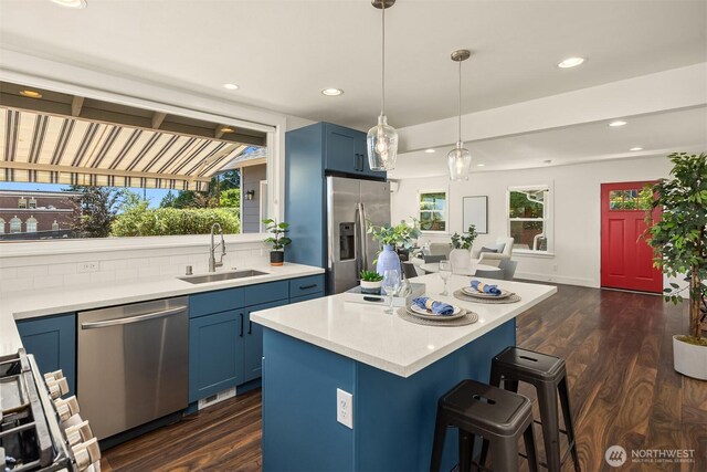 7554 34th Ave SW, Seattle, WA 98126 - kitchen featuring appliances with stainless steel finishes, blue cabinetry, a kitchen breakfast bar, and recessed lighting