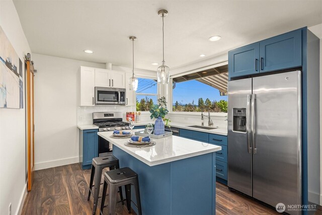 7554 34th Ave SW, Seattle, WA 98126 - kitchen with stainless steel appliances, blue cabinetry, backsplash, dark wood-style flooring, and a kitchen bar