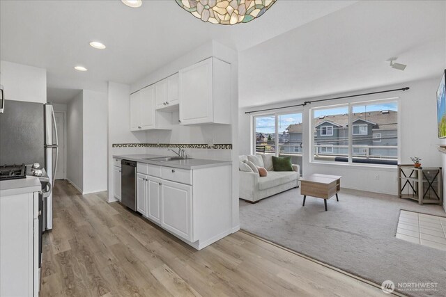 2448 NW 59th St Unit 301, Seattle, WA 98107 - kitchen featuring light countertops, stainless steel dishwasher, white cabinets, light wood-style floors, and recessed lighting
