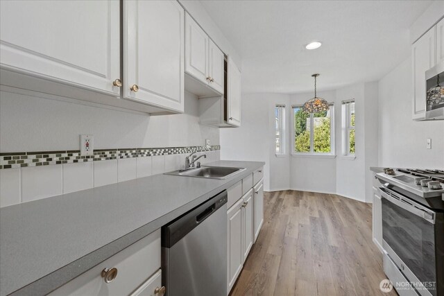 2448 NW 59th St Unit 301, Seattle, WA 98107 - kitchen with stainless steel appliances, decorative backsplash, white cabinetry, light wood-style floors, and recessed lighting