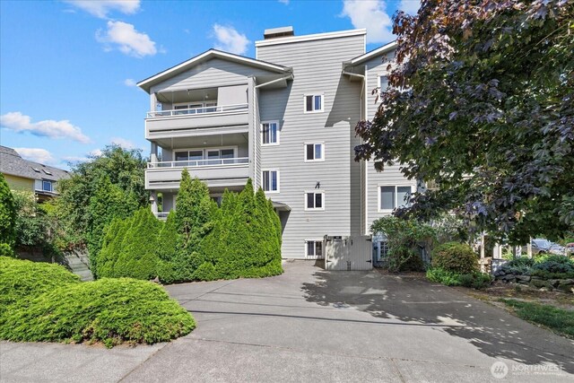 2448 NW 59th St Unit 301, Seattle, WA 98107 - rear view of property with a balcony, concrete driveway, and a chimney