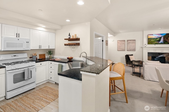 412 228th St SW Unit F101, Bothell, WA 98021 - kitchen featuring white appliances, a peninsula, a breakfast bar area, open floor plan, and white cabinetry