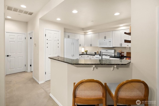 412 228th St SW Unit F101, Bothell, WA 98021 - kitchen featuring white appliances, light colored carpet, white cabinetry, a peninsula, and dark stone counters